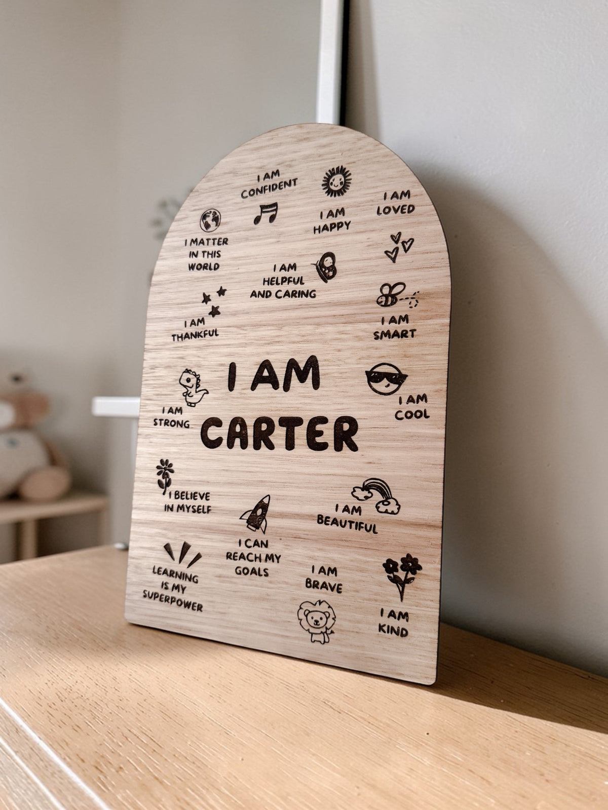 Wooden plaque with 'I AM' affirmations on a wooden surface