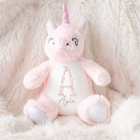 A personalised pink unicorn soft toy with a floral initial and personalised name.